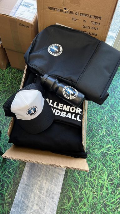 Boîte contenant des vêtements et accessoires de la marque, incluant un sac, un T-shirt et une casquette.